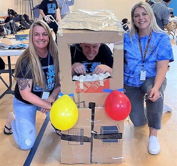 Team members posing with the cardboard time machine they built